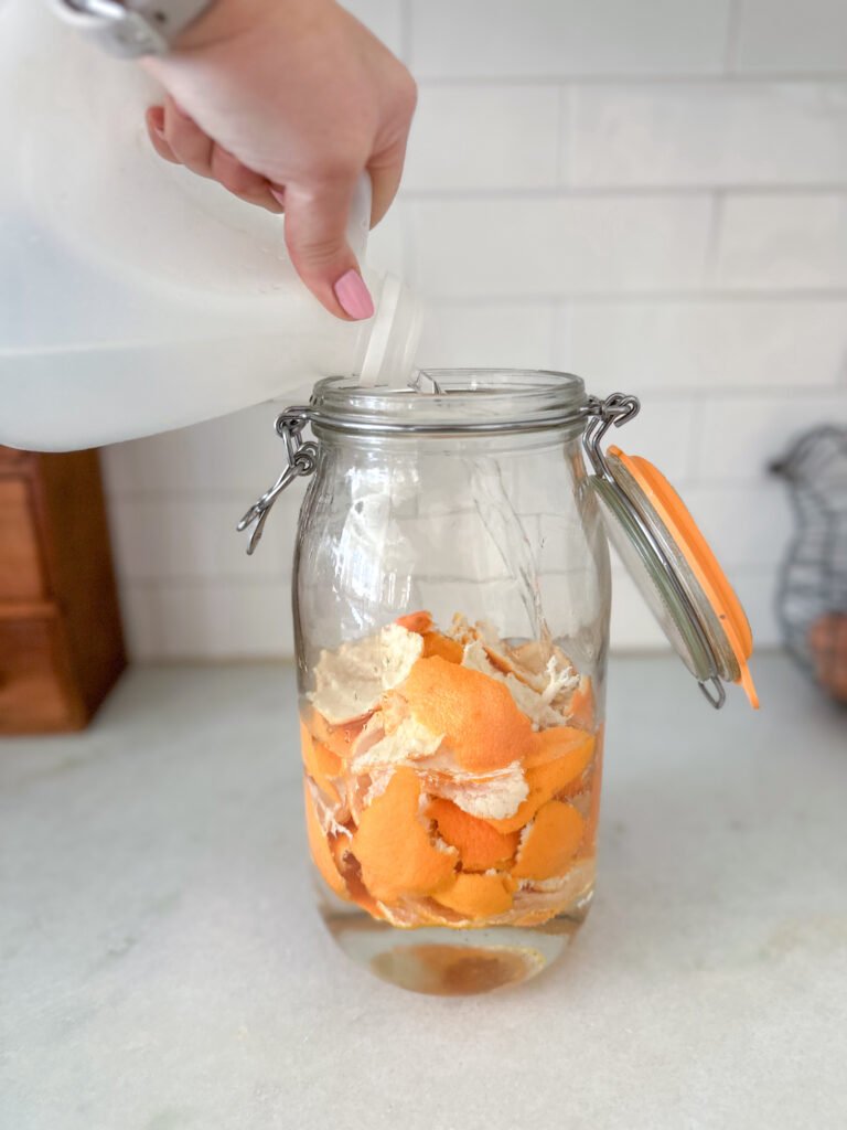 pouring vinegar onto oranges for all purpose cleaner