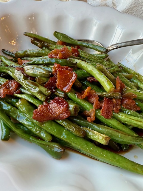 Spoon and green beans in white dish
