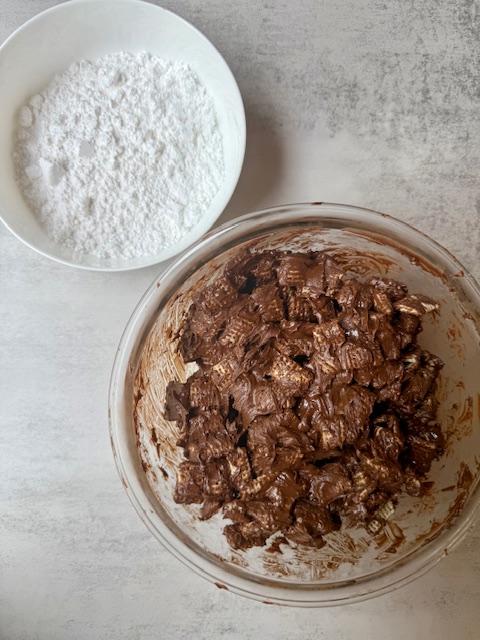Chex Cereal covered in chocolate pistachio mixtures and powdered sugar in bowls
