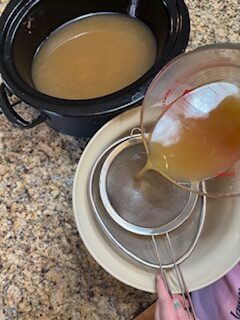 Straining chicken broth a second time in fine mesh strainer