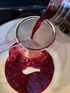 Double straining cherry juice into dutch oven