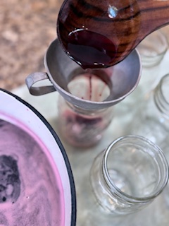 Ladling cherry limemade mixture into mason jars