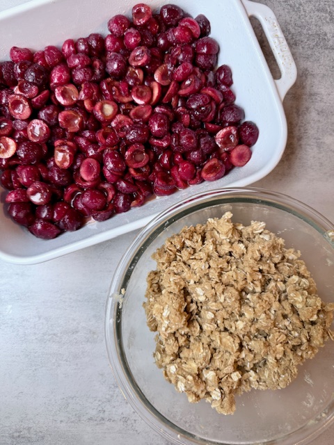 Cherries in baking dish and crumble in glass mixing bowl