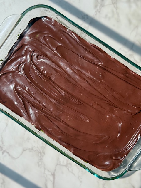 Rice krispie treats topped with pistachio cream and melted chocolate