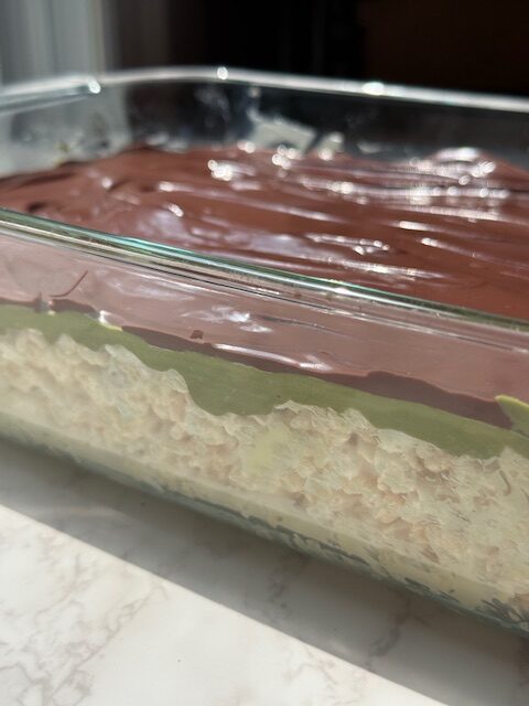 Rice krispie treats topped with pistachio cream and melted chocolate