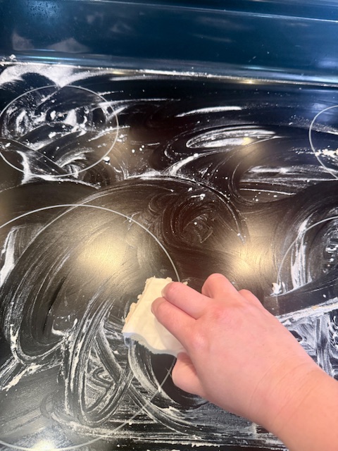 Scrubbing glass stove top with baking soda and vinegar