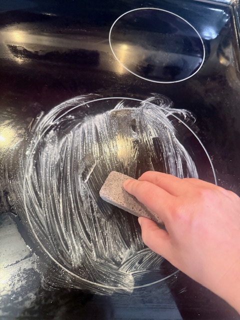 Scrubbing glass stove top with scouring stick