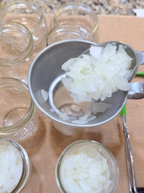 spooning diced onions into mason jars