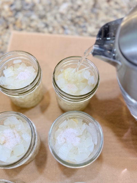 pouring water into jars with diced onions