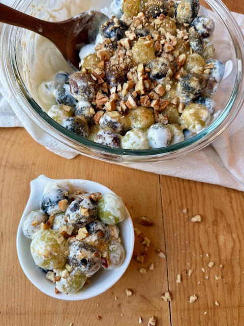 Grape Salad in small white bowl on wood cutting board