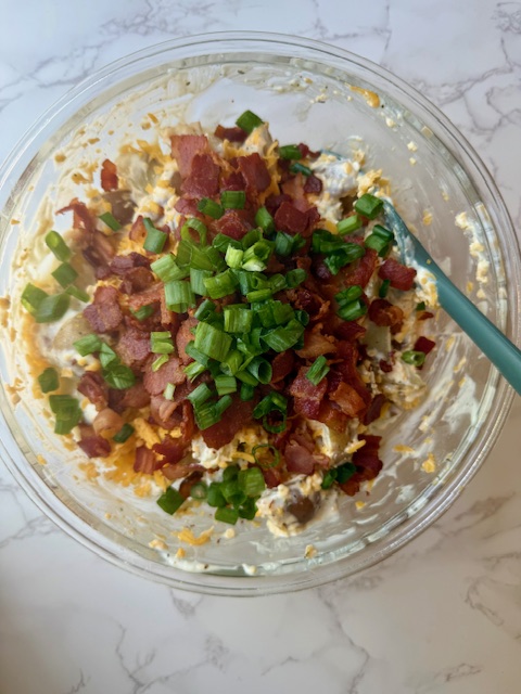 Adding bacon and green onion to potato salad
