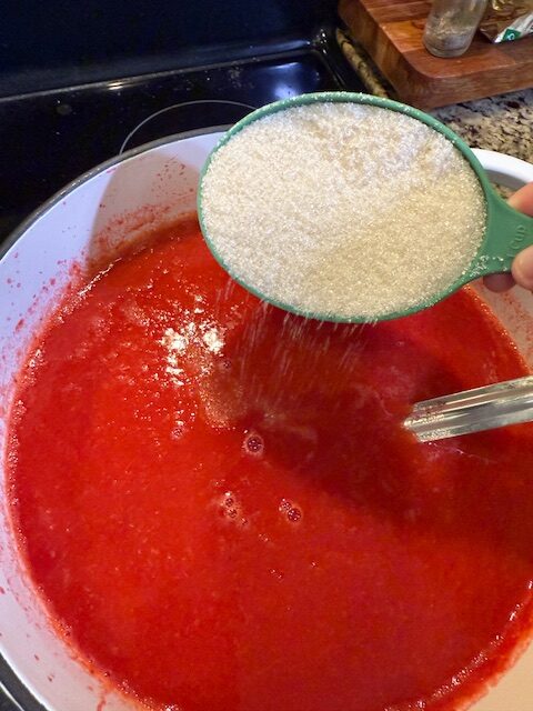 pouring sugar into strawberry lemonade concentrate