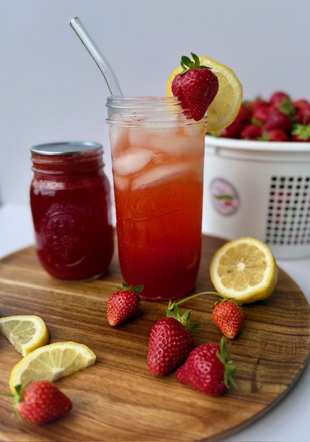 Strawberry Lemonade Concentrate in mason jar with fresh strawberries and lemons