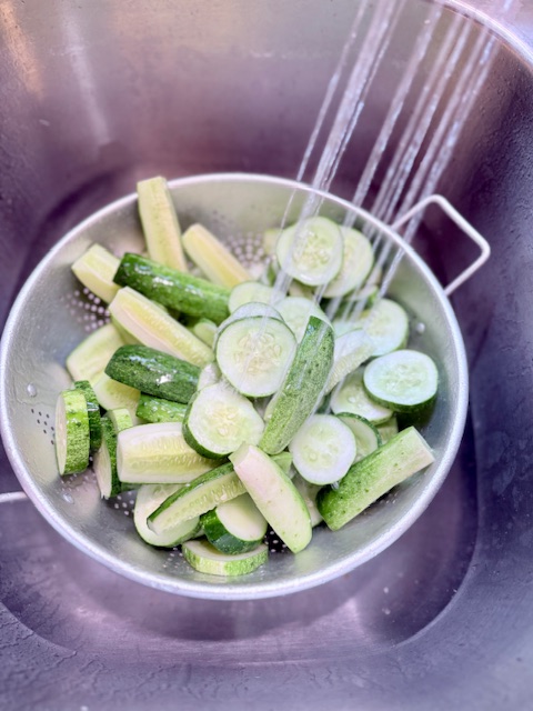 cucumber slices in colander being rinsed